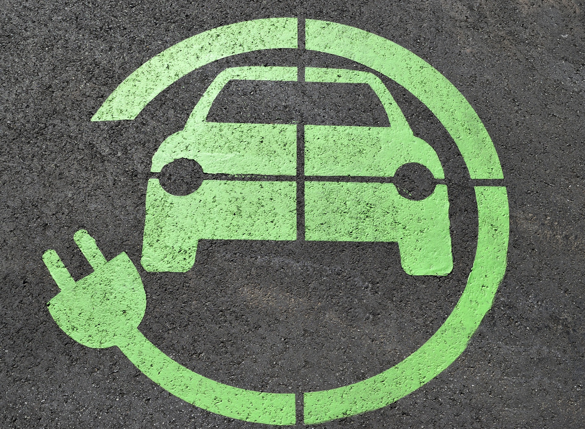 Elektromos autók. Aszfaltra festett zöld színű elektromos autó szimbólum