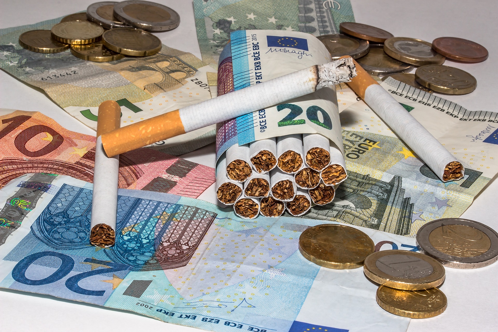 Cigaretták és Eurók egy asztalon. Fém és papírpénz együtt. A kép a cigaretta és a pénz viszonyát akarja szimbolizálni.
